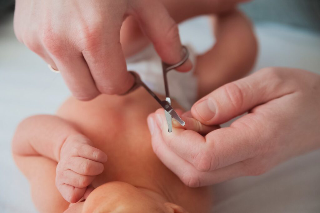 father cuts the newborn s nails manicure a child close up newborn baby care concept e1634537369435